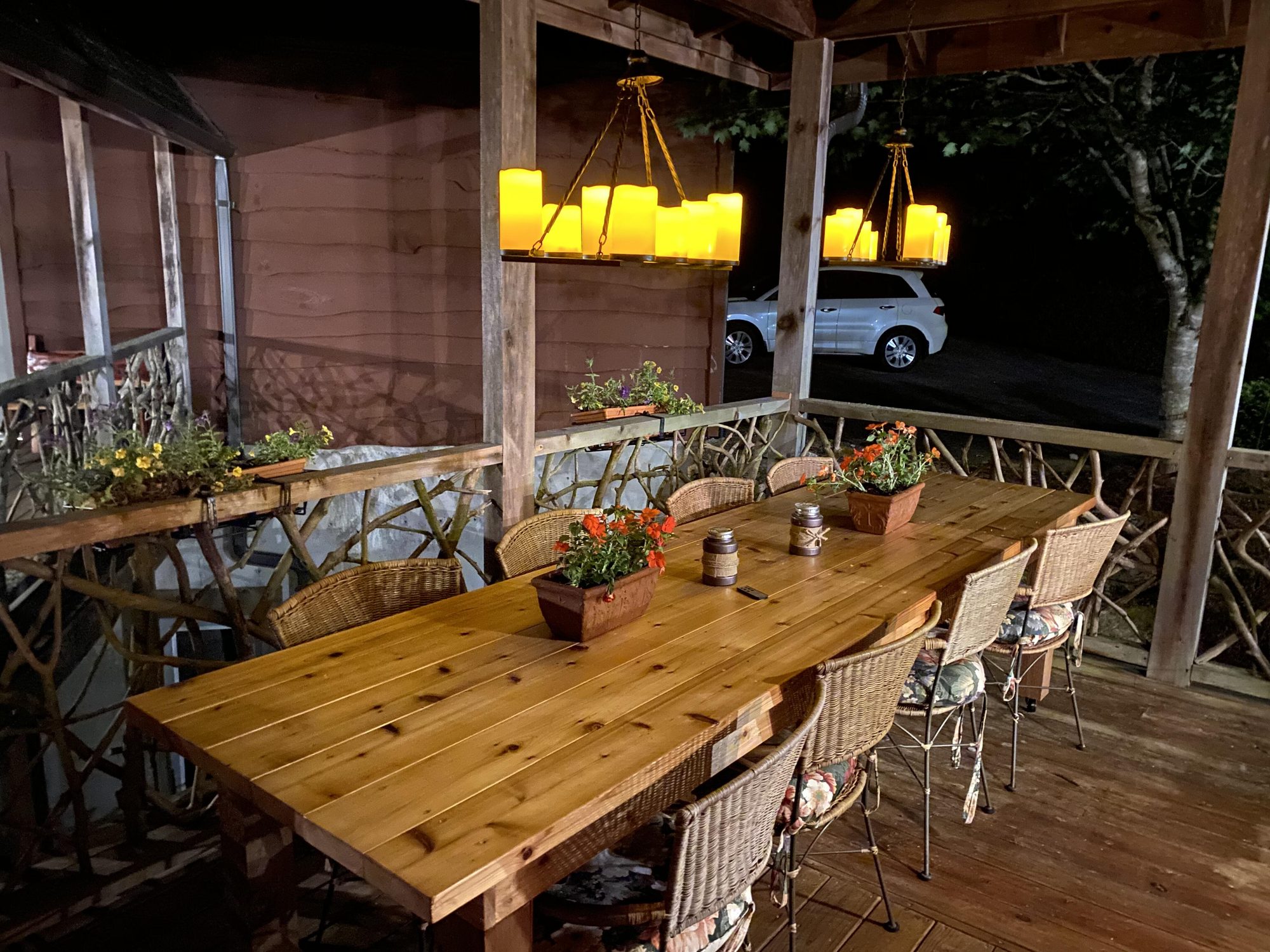 Farm table on the covered deck set for eight on a summer evening