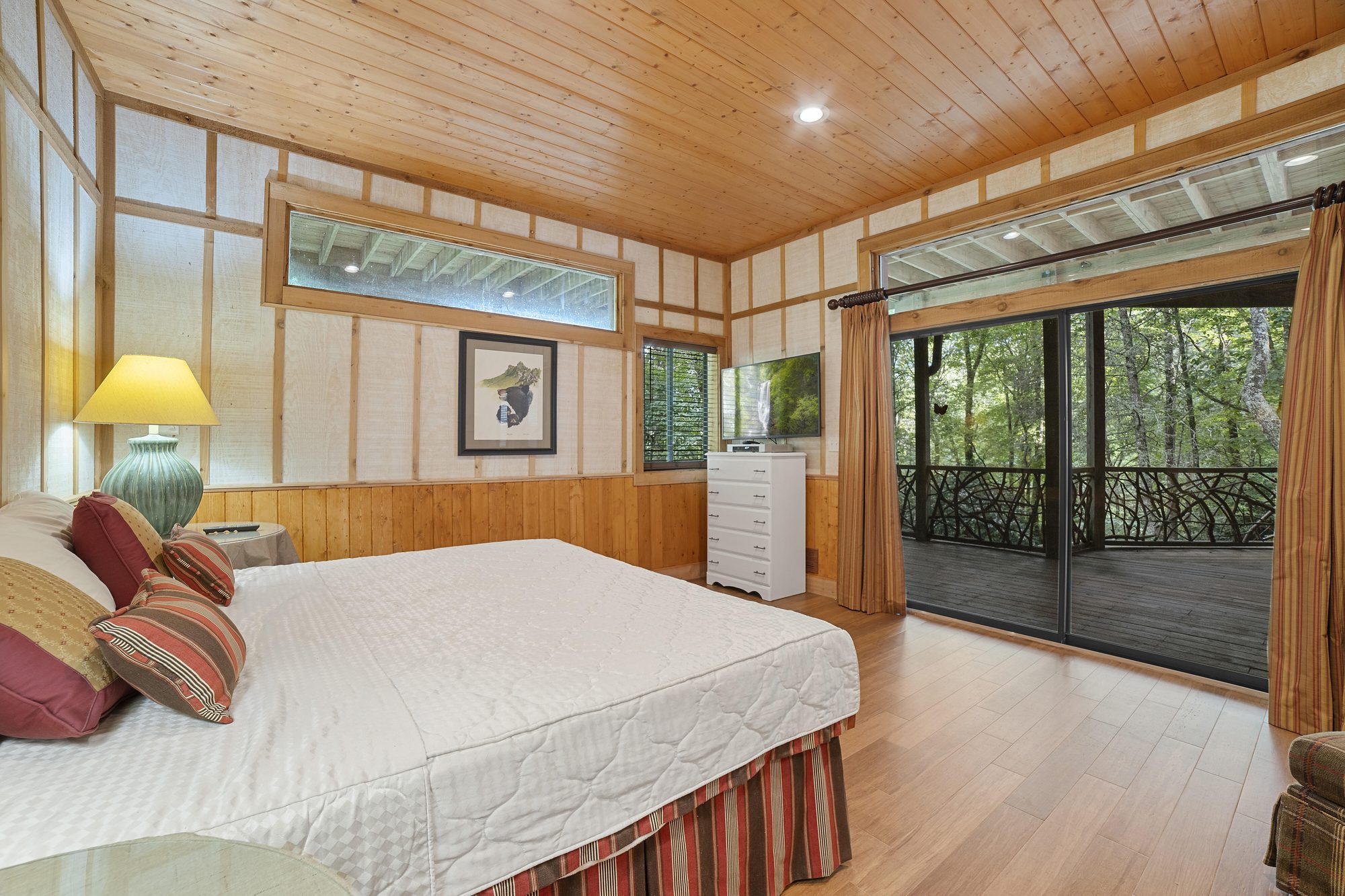Lower-level king suite with wood walls and forest light