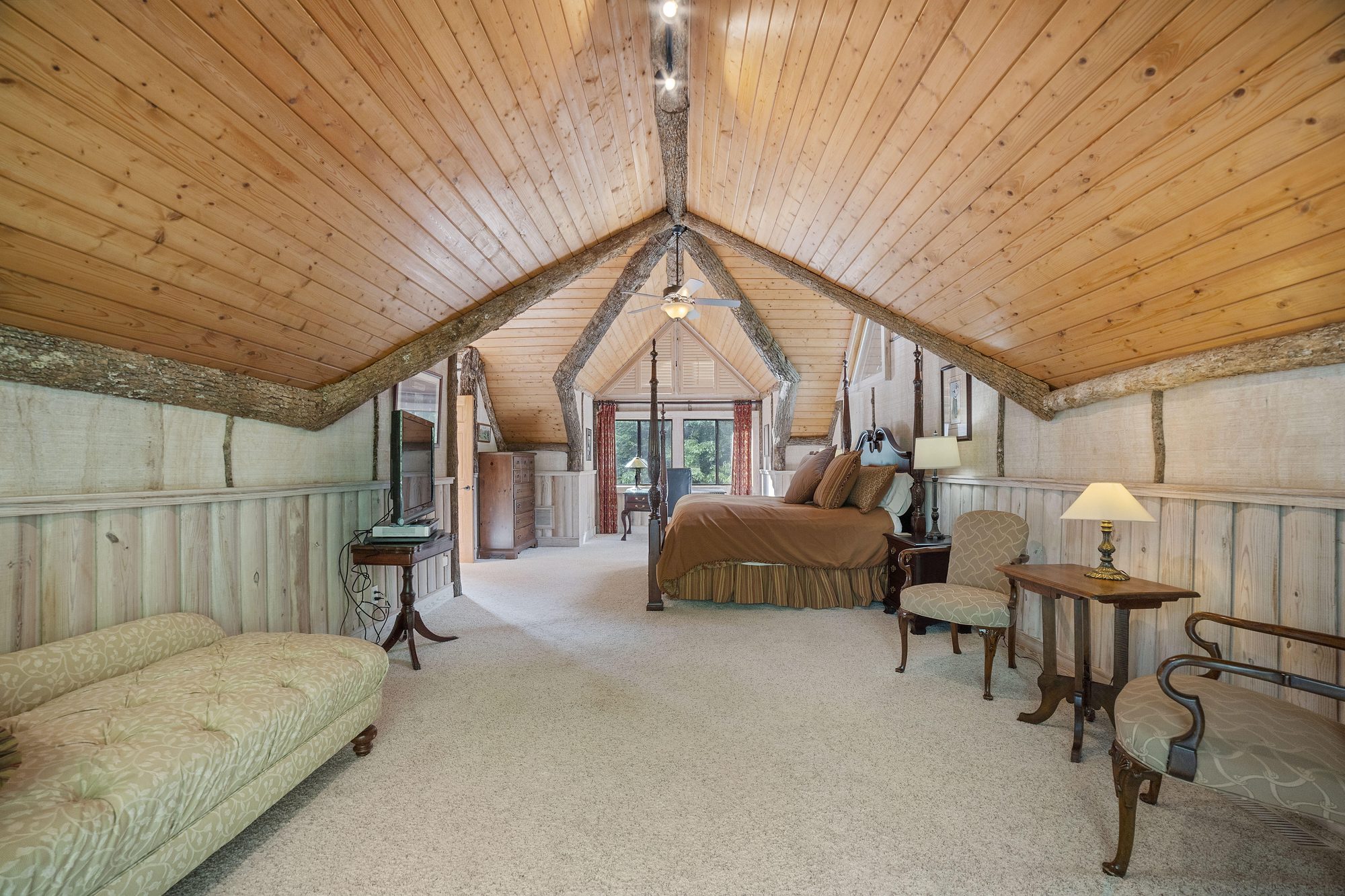 Upper primary suite with four-poster bed and cathedral log ceiling