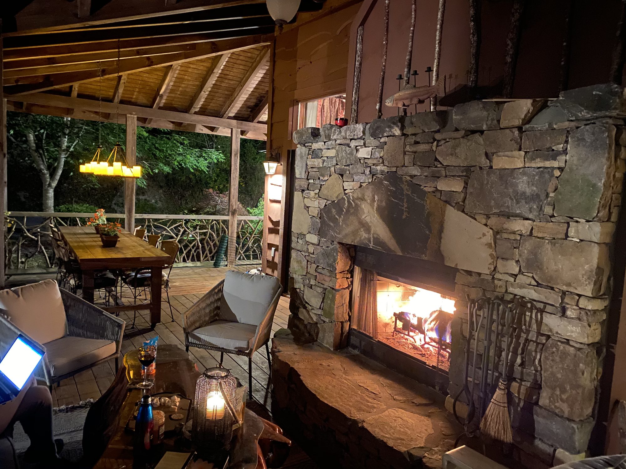 Fire lit in the outdoor fireplace on the covered porch at dusk